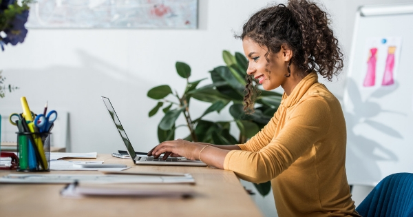 Steps to Promote a Wellness Workshop - Whole Family Coaching. Woman sitting at a desk typing on a laptop.